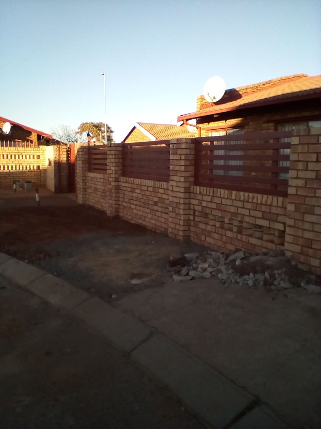 Maroon steel panels fitted between the pillars along the brick boundary wall