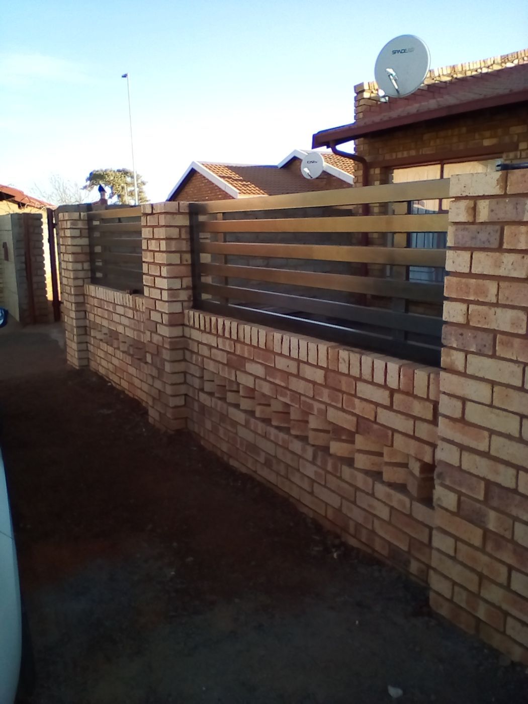 Matching steel slat panels fitted on top of the brick boundary wall